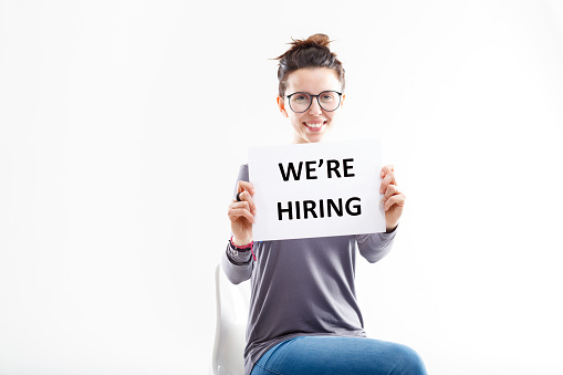 hiring sign held by your next colleague, a smiling woman with glasses that will work with you in your future workplace for, say, two or three days: what a happiness.