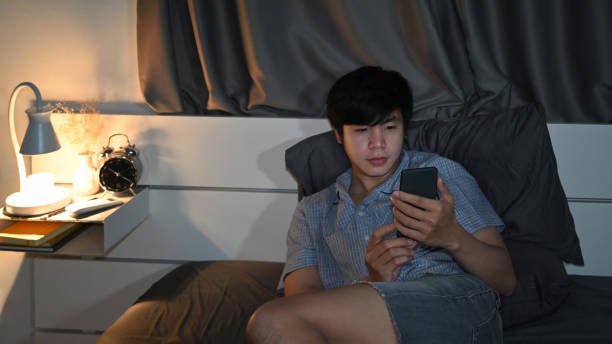 istock Man in casual pajama lying on bed and using smart phone. 1359625226