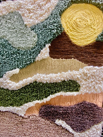 Vertical close up of part of handmade creative textile art design of landscape with sun and land art created from cotton wool and other fabrics
