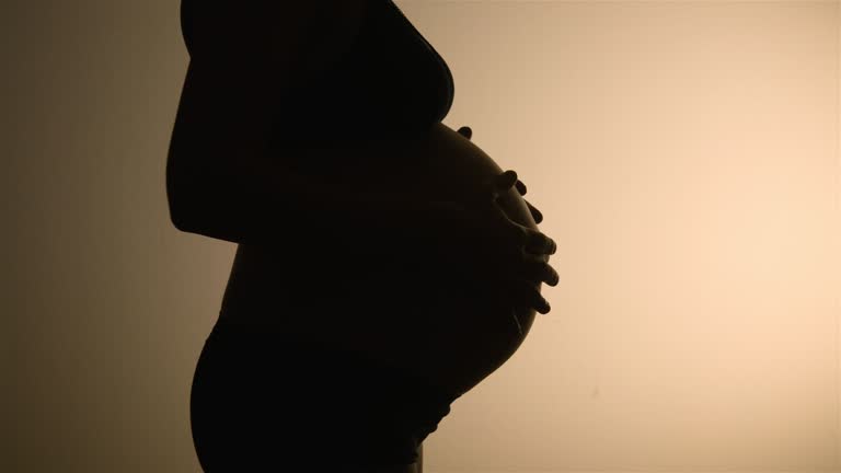 Beautiful SILHOUETTED CLOSEUP of a very pregnant belly close to giving birth