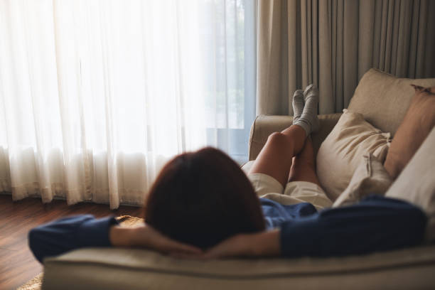 A woman lying and relaxing on a sofa at home A woman lying and relaxing on a sofa at home napping stock pictures, royalty-free photos & images