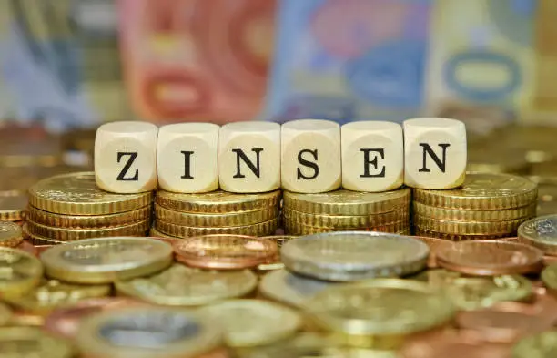 The word "Zinsen" in German language, on a stack of euro coins and banknotes.