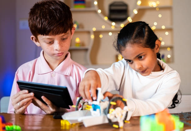 les enfants sont occupés à fabriquer un robot de bricolage en regardant à partir d’une tablette numérique à la maison concept d’expérience robotique pour enfants, de convivialité, d’apprentissage et de développement de l’enfance. - enfant prodige photos et images de collection