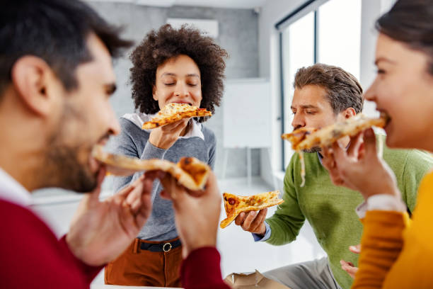 businesspeople eating lunch at the office. a small group of multiracial colleagues sitting at the office and enjoying pizza for lung on their lunch break. - pizza eating african descent lunch imagens e fotografias de stock