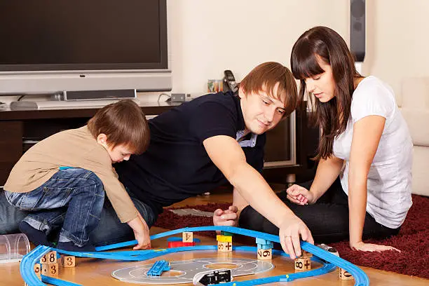 Family is playing toy railroad and bricks
