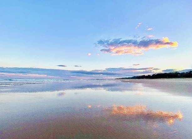 Cloud Reflection in Beach Sand Horizontal seascape of pastel color sunset sky with cloud reflection in waters edge on ocean sand with coastline horizon at Brunswick Heads beach NSW Australia reflection lake stock pictures, royalty-free photos & images