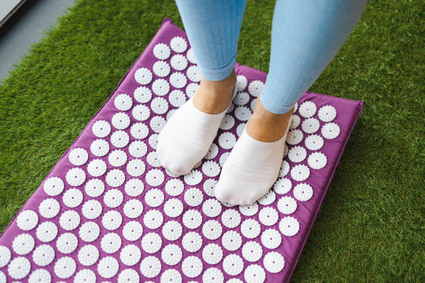 Woman standing on acupressure mat Woman standing on acupressure mat acupuncture mat stock pictures, royalty-free photos & images