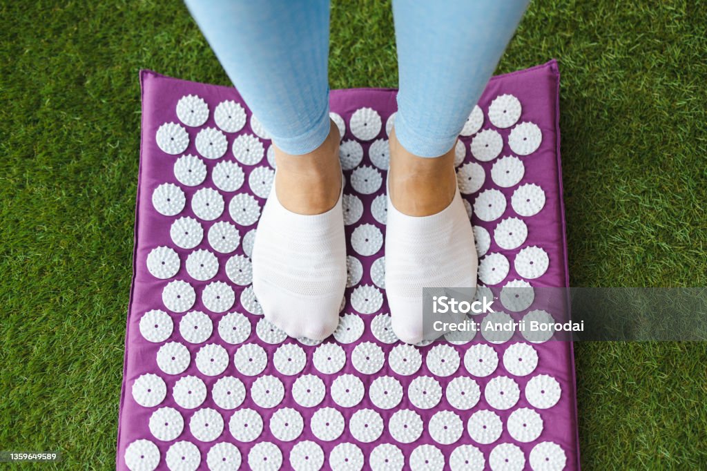 Women's feet standing on acupressure mat. Acupuncture massage Mat Stock Photo