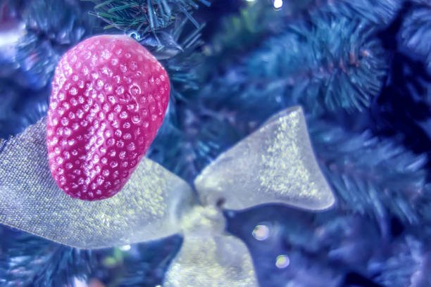 Christmas background or card: red strawberries on a blue Christmas tree decorated with an white bow.
