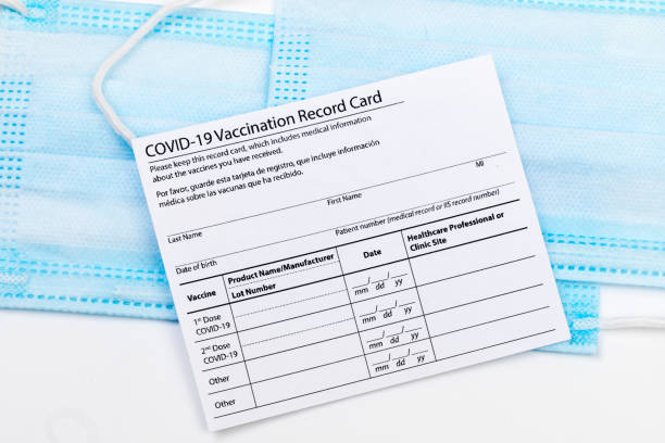 istock Coronavirus vaccination record card. Protective mask divided into two parts. Concept of defeating Covid-19 1359657145