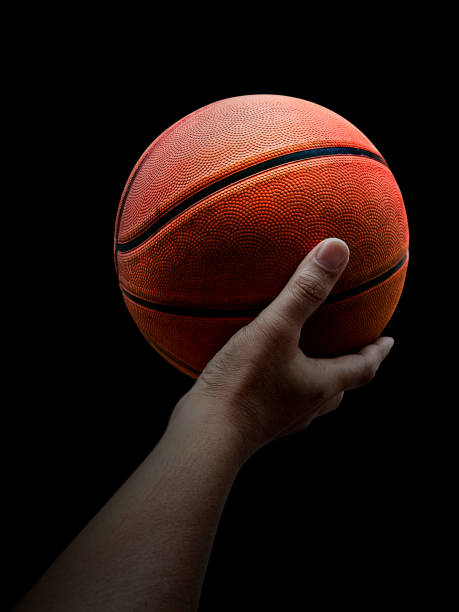 istock Basketball player holding a ball against black background 1359659208