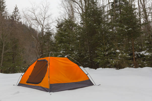 orange touristic tent in a winter forest