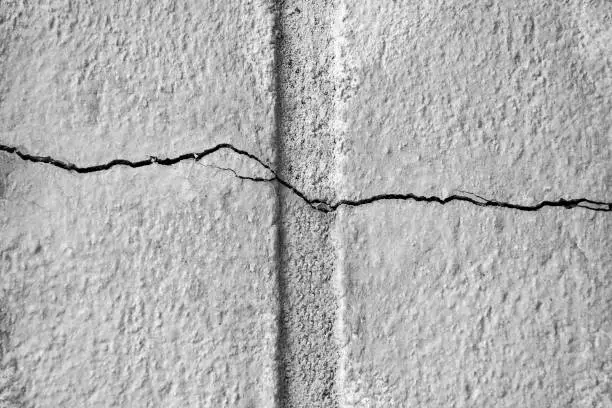 Sinuous horizontal thin crack on gray plastered surface of wall of old building. Copy space. Selective focus.