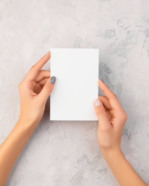 istock Manicured womans hands holding postcard on grey concrete background 1359662570