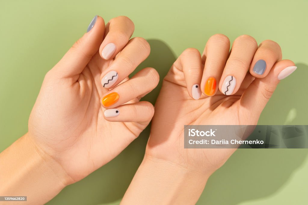 Close up womans hands with trendy minimal manicure on green background. Spring summer nail design Close up womans hands with trendy minimal manicure on green background. Spring summer nail design. Beauty salon concept. Fingernail Stock Photo