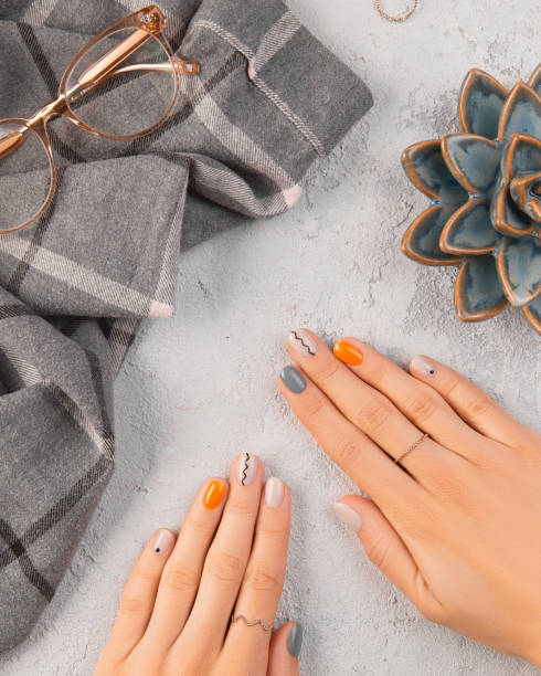 Womans hands with trendy minimal manicure on gray background. Summer spring nail design
