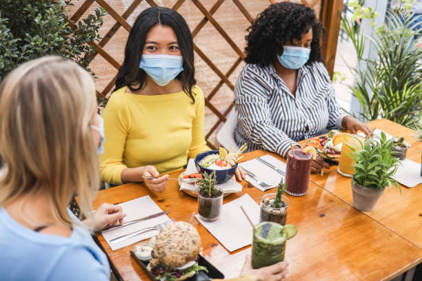 istock Happy multiracial young friends eating at brunch restaurant during coronavirus outbreak - Focus on asian girl face 1359664697