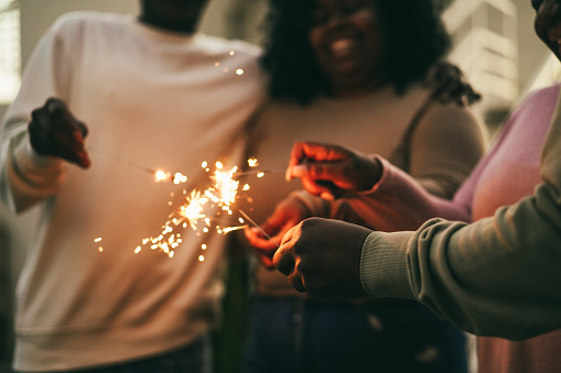 Happy african family using sparklers outdoor at home - Focus on right hand