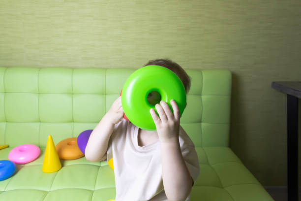 istock The child is having fun playing a bright pyramid educational toy, sitting on a green sofa. 1359665722