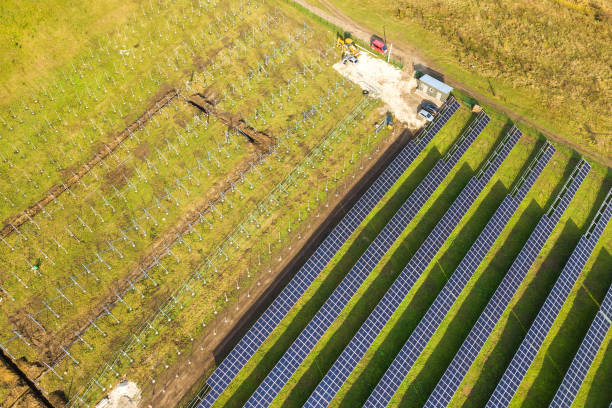 vue aérienne d’une centrale solaire en construction sur terrain vert. assemblage de panneaux électriques pour la production d’énergie écologique propre. - environmental conservation built structure solar power station building exterior photos et images de collection