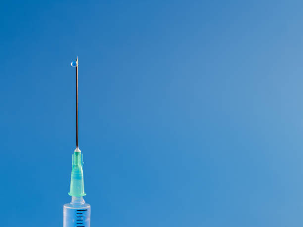 istock Injection with drop close up view on blue background 1359666873