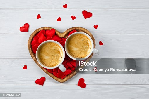 istock Two cups of coffee on a tray in the shape of a heart and red hearts on a white wooden background. Festive card for Valentines Day 1359667052
