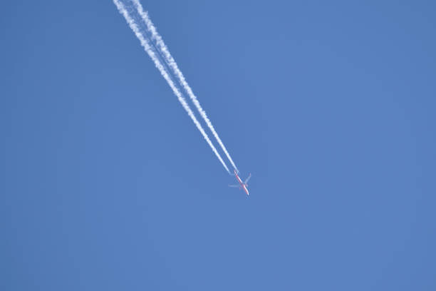istock Distant passenger jet plane flying on high altitude on clear blue sky leaving white smoke trace of contrail behind. Air transportation concept 1359667452
