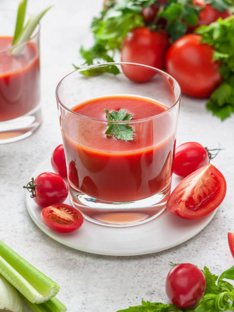 istock Tomato juice in a glass on a white backround 1359668132