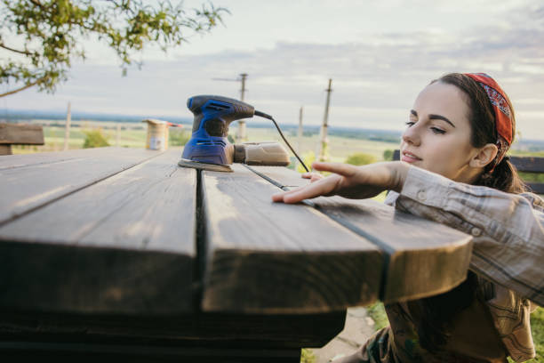 istock Woman checks the surface of her garden table after using a sanding machine 1359668286