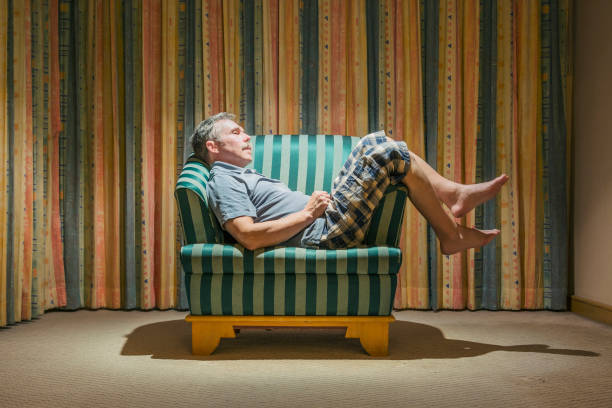 un turista anziano appisolato su una sedia in un hotel economico - slouch hat foto e immagini stock