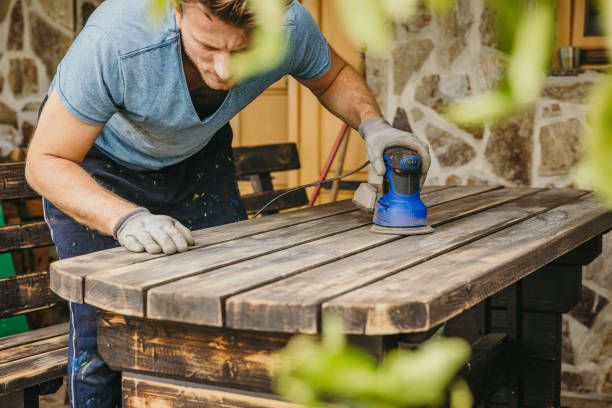 istock Man with sanding machine on a wooden table looks at the table surface after sanding it 1359668626
