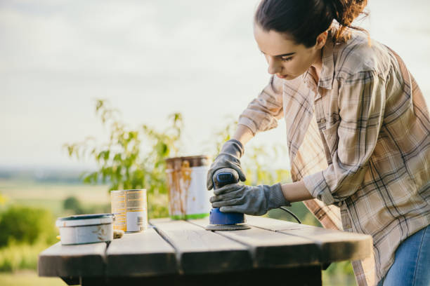 istock Young woman with brown hair using a sanding machine on her garden table 1359669178