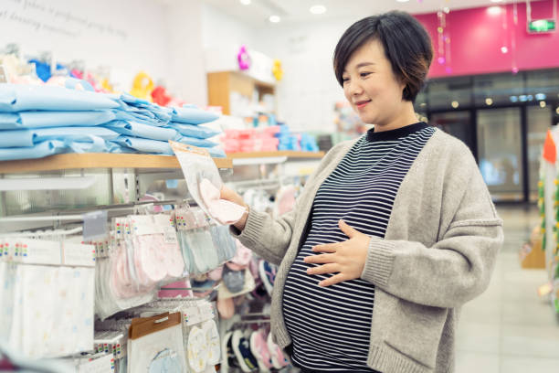 donna incinta che sceglie i vestiti del bambino - human pregnancy clothing shopping retail foto e immagini stock