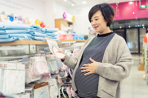 Pregnant woman choosing baby clothes
