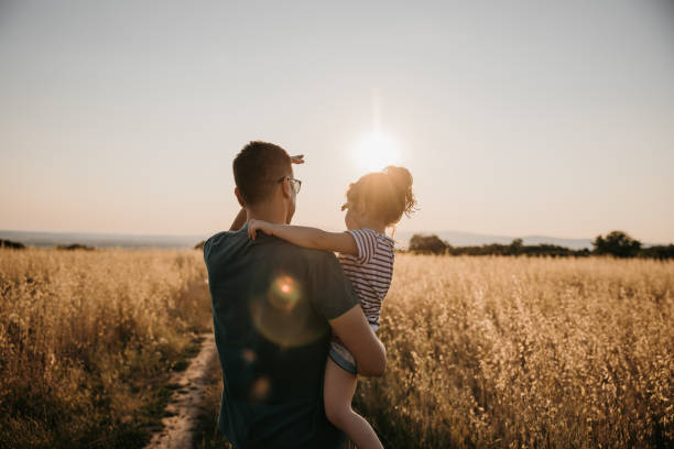istock Back view of father while carrying his daughter and looking away 1359673014