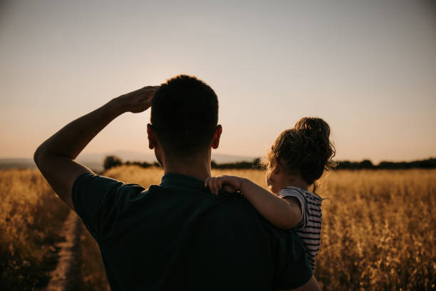 istock Back view of father while carrying his daughter and looking away 1359673052