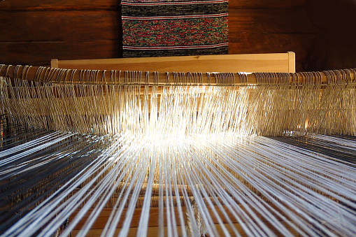 Vintage wooden hand loom. Ancient weaving loom in interior of  wooden log hut, sunlight