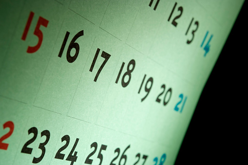 Close-up of green calendar against black background with spotlight.