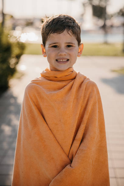 istock Cute boy wearing a tovel while standing in water park 1359673632