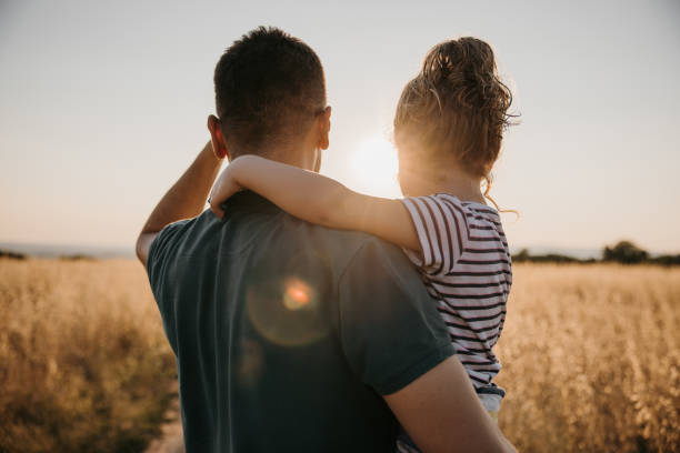 istock Back view of father while carrying his daughter and looking away 1359673666