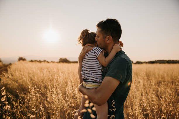 istock Father embracing daughter in nature while standing in grass field 1359673686