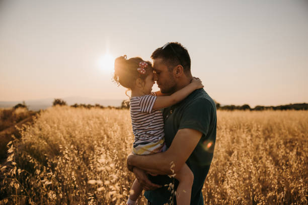 istock Father playing with his daughter in nature while standing in grass field 1359673731