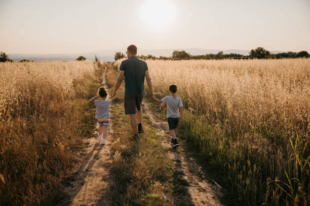 istock Back view of father while walking on dirt road with his two kids 1359673826