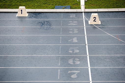 Empty and wet track and field stadium due to heavy rain.