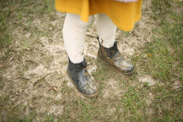 istock Yellow rain coat black boots dirt dirty rainy day 1359678971