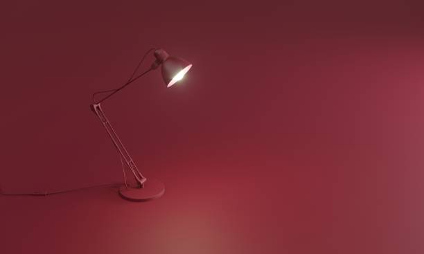 Glowing desk lamp on red floor Modern glowing desk lamp is standing on red background. desk lamp stock pictures, royalty-free photos & images