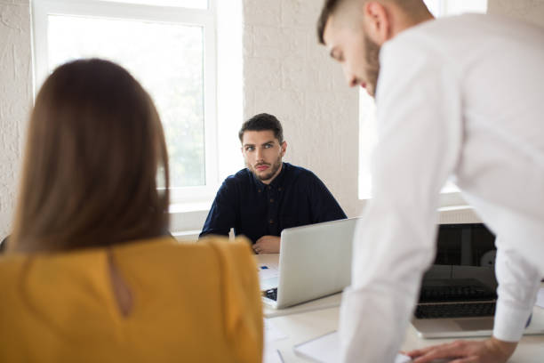 istock Young businessman in shirt thoughtfully looking aside with laptop. Creative people working together while spending time in modern office 1359681175