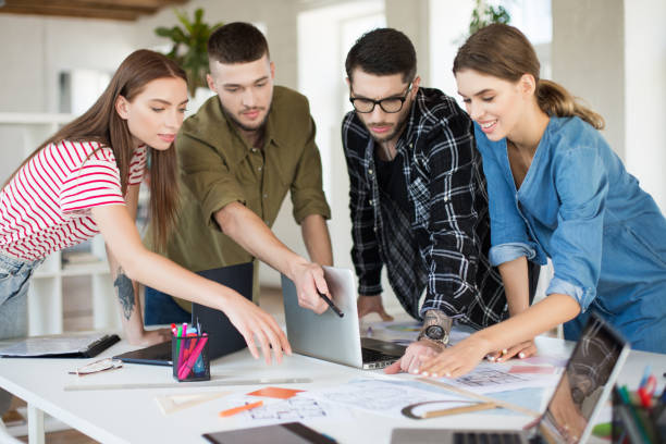 istock Young creative people working together with laptop. Group of cool guys working on new project while spending time in modern office 1359681330