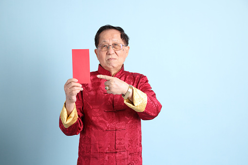 The senior Asian man wearing traditional Chinese shirt on the blue background.