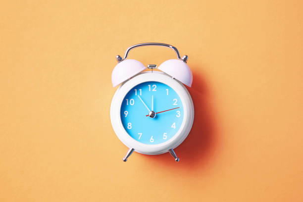 istock White Alarm Clock On Salmon Background 1359687884